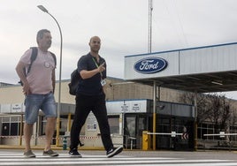 Dos trabajadores, frente a la puerta de acceso a la planta de Ford en Almussafes.