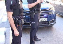 Dos policías nacionales junto a un coche patrulla.