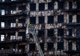 Un grupo de bomberos inspecciona la fachada de la finca incendiada en Campanar.