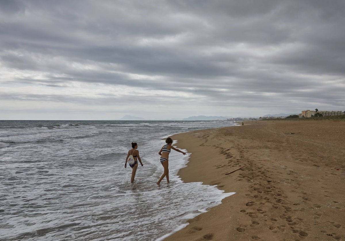 Dos mujeres caminan por una playa de Tavernes de la Valldigna en la que tres personas fallecieron el verano pasado.