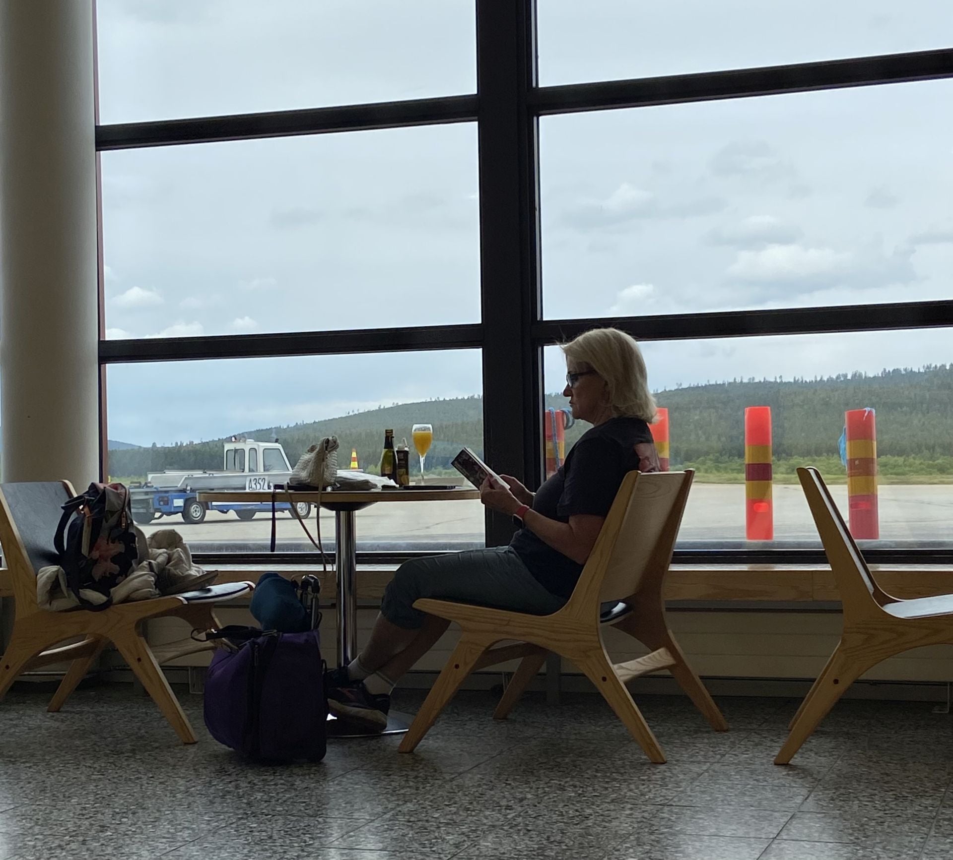 Señora esperando un avión con una mimosa de cava