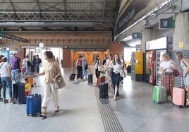 Varias personas esperando en la estación de tren para comenzar sus vacaciones.