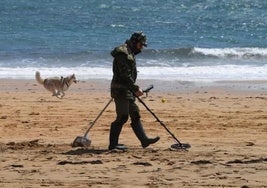 Un hombre utiliza un detector de metales en una playa.