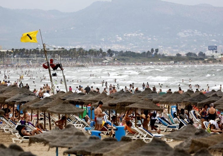La bandera amarilla ondea en la playa de la Malvarrosa este domingo.