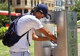 Un joven rellena su botella de agua en una fuente en Valencia.