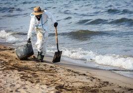 Un operario retira el fuel de las playas.