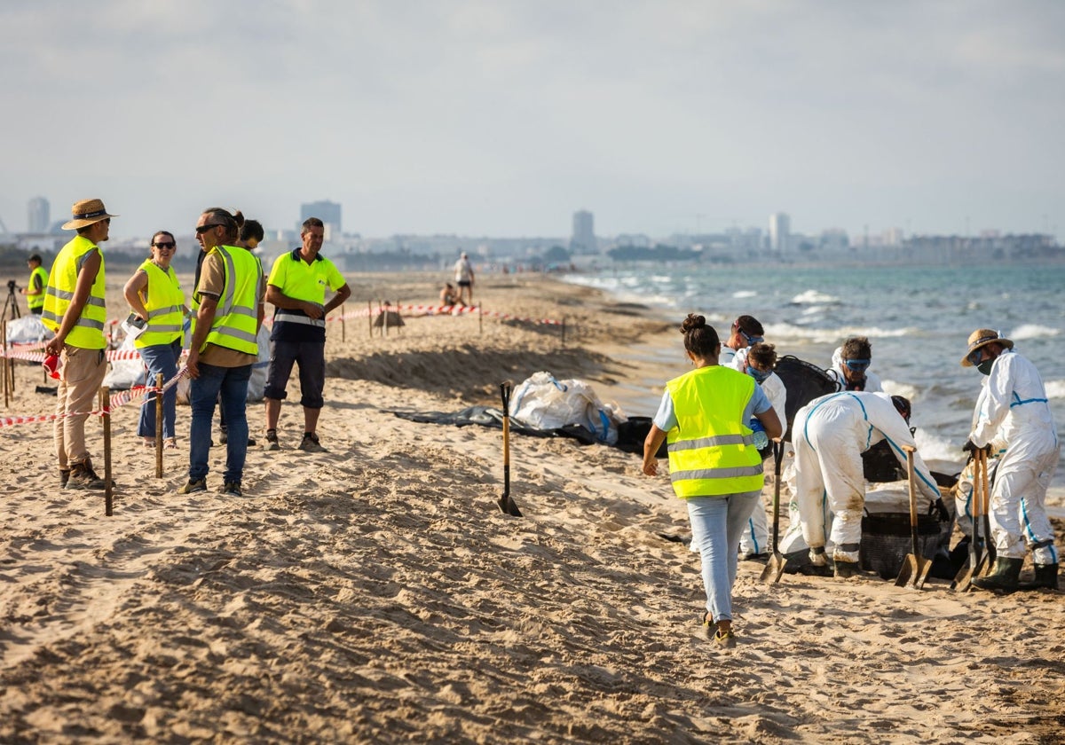 Operarios retirando los restos de fuel en la playa.