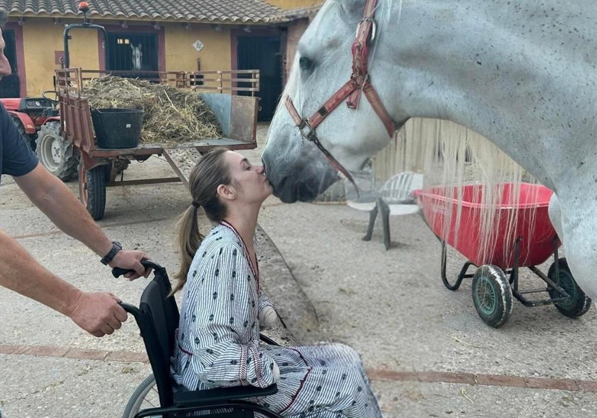 Carla Maronda, muy aficionada a la hípica, besa a su caballo Bolero desde su silla de ruedas.