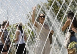 Varias personas se refrescan en la Ciudad de las Artes y las Ciencias de Valencia.