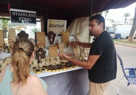 Bernardo Núñez atiende a una clienta durante la feria medieval de la playa de la Pobla de Farnals.