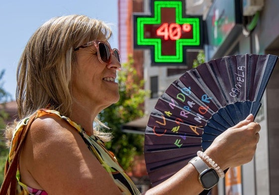 Una mujer calma el calor con un abanico.