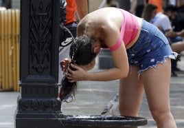 Una joven se refresca en una fuente en una imagen de archivo.