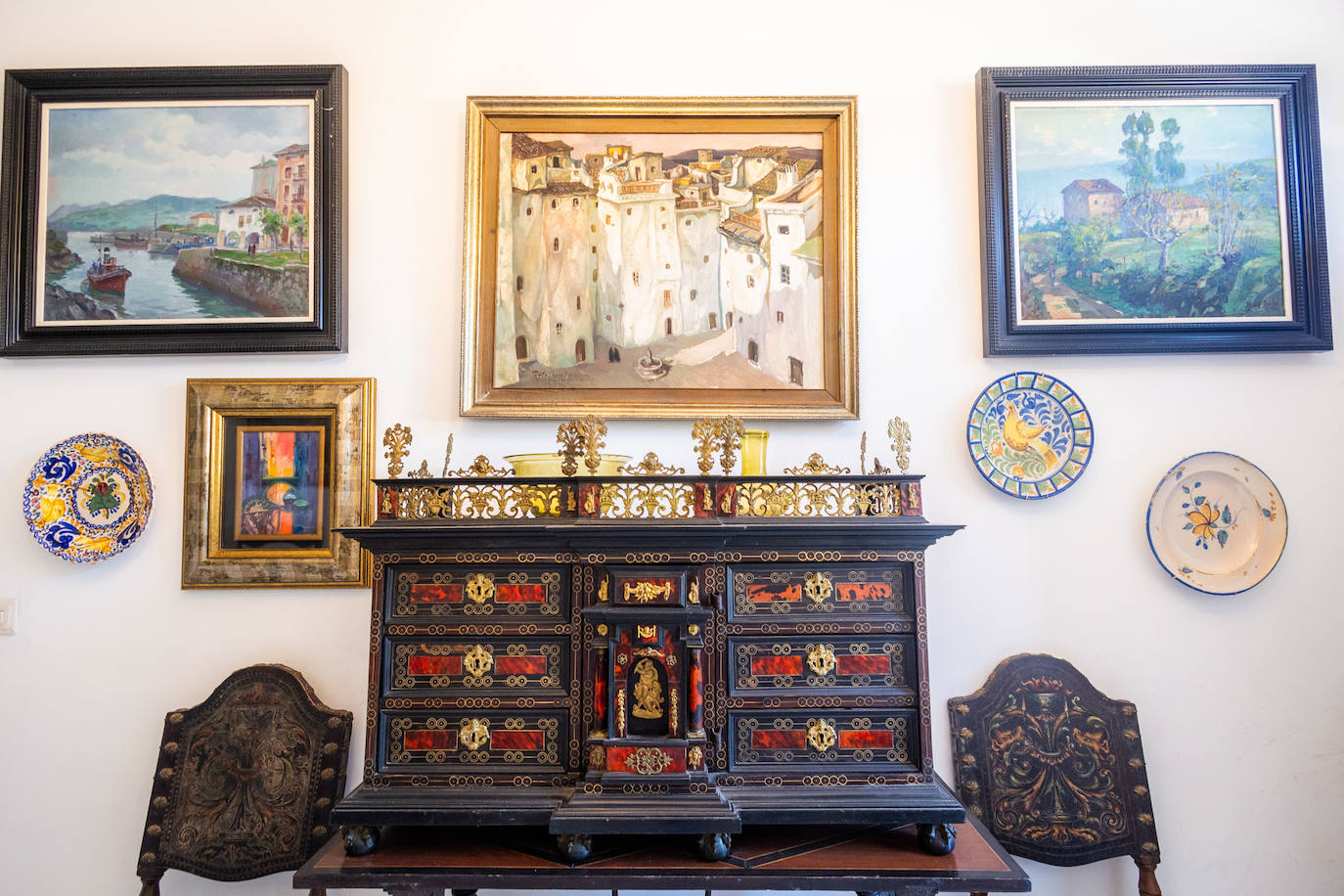 Mueble de la casa de los bisabuelos con incrustaciones en oro y sillas en cuero repujado que preside una de las paredes del recibidor de la casa.