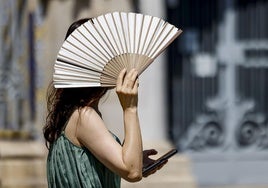 Una mujer se protege del sol con un abanico en Valencia.