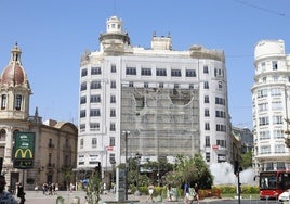 Retirada del anuncio publicitario de la fachada de una finca de la plaza del Ayuntamiento de Valencia.