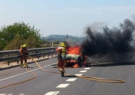 Los bomberos intervienen para controlar las llamas del vehículo incendiado.