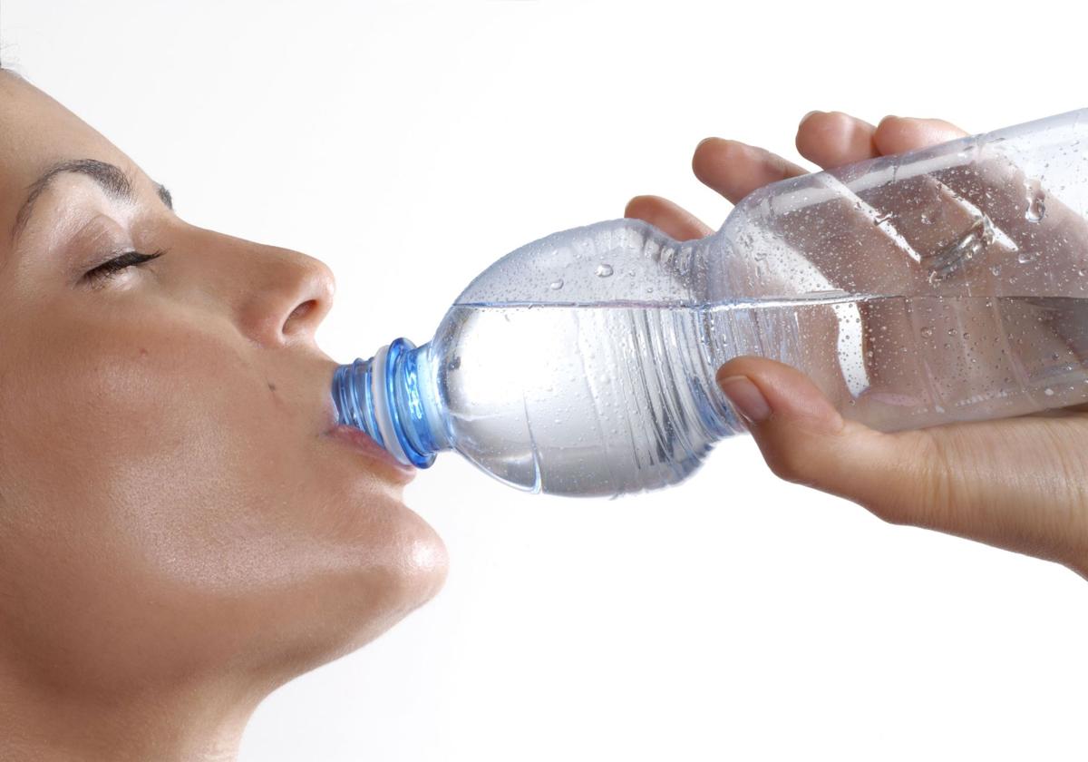 Mujer bebiendo agua de una botella.