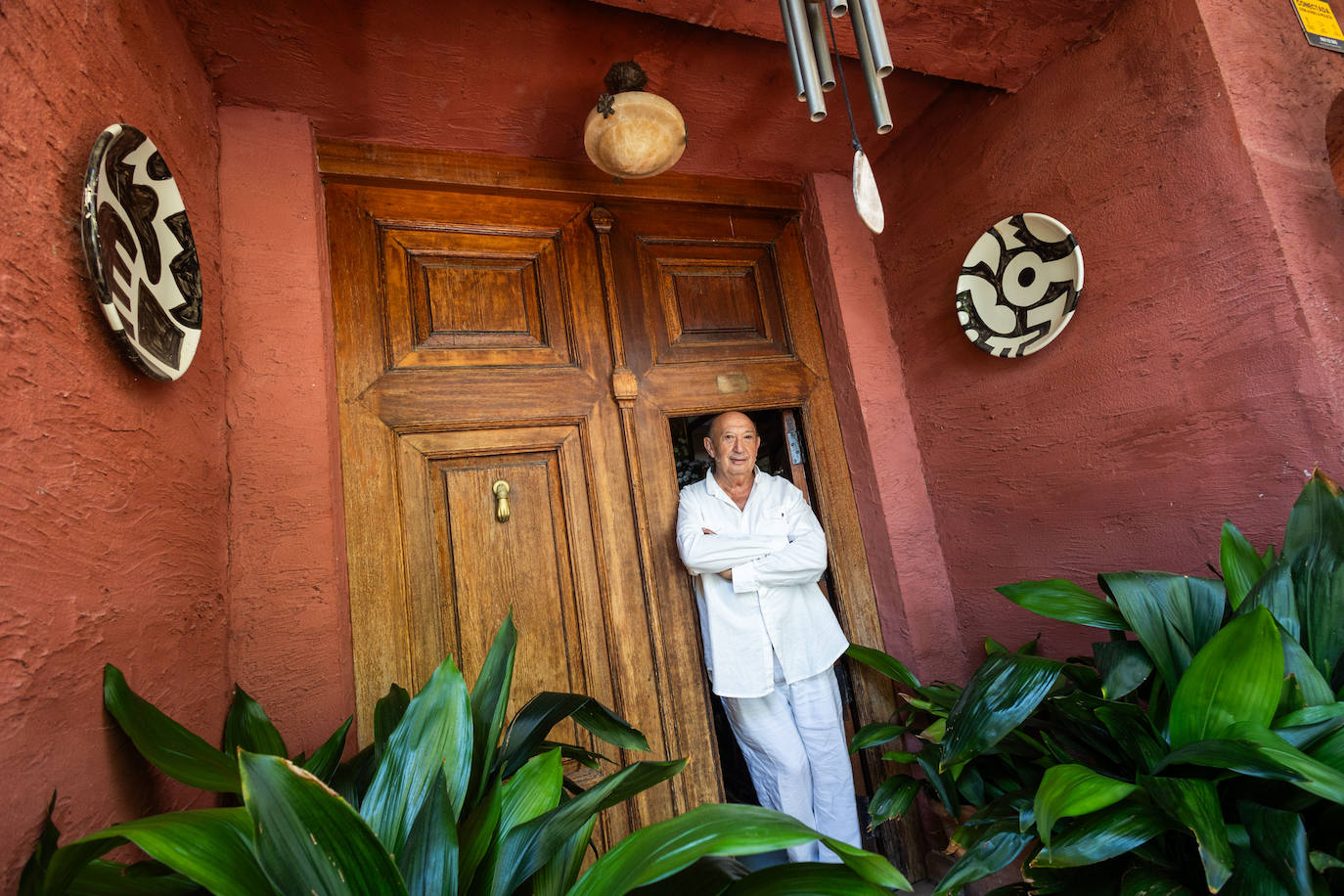 El diseñador, en la puerta de su casa, que conserva los tiradores antiguos, siempre con las plantas muy presentes.