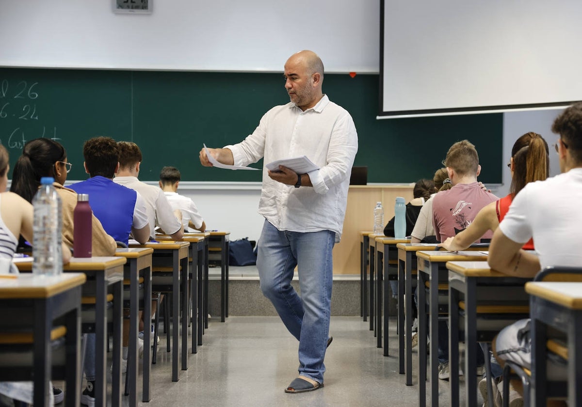 Un profesor reparte exámenes en un aula de la Comunitat.