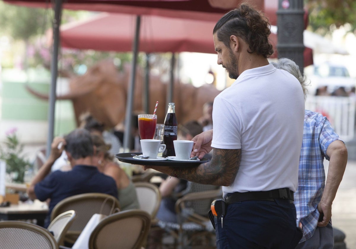 Un camarerosirve a los clientes de una terraza.