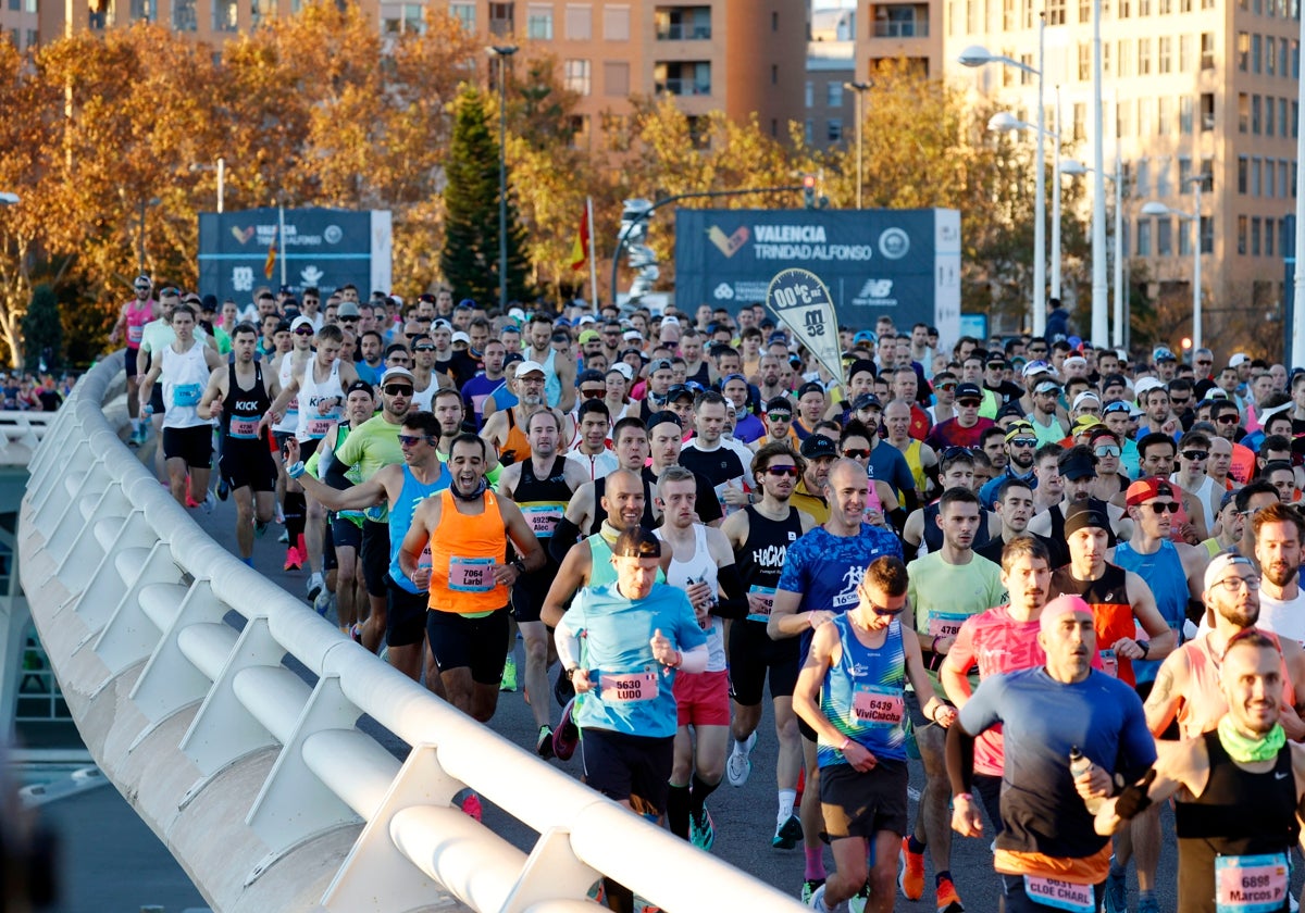 Los corredores cruzan el puente de Monteolivete después de darse la salida del Maratón de Valencia de 2023.