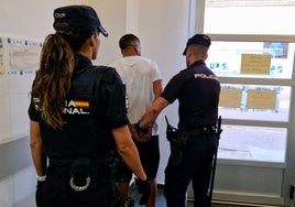 Dos policías trasladan al detenido.