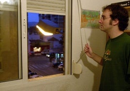 Un hombre se asoma por la ventana al no poder dormir por el calor.