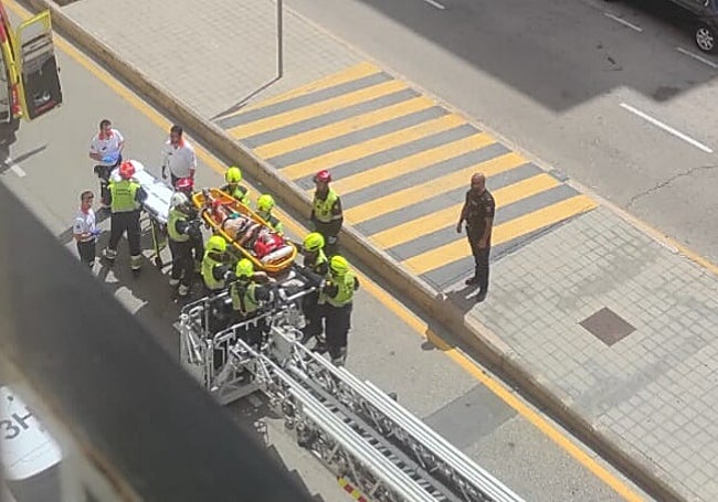 Un grupo de bomberos traslada a la víctima en una camilla.