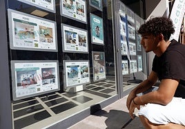 Un joven mira ofertas de alquiler en una inmobiliaria.