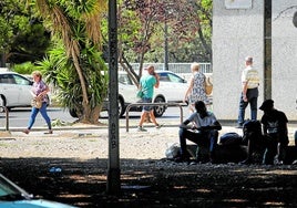 Varias personas sentadas en un parque cerca de la estación de autobuses.