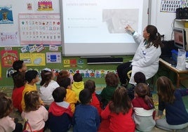 Una enfermera explica salud bucodental a unos niños en un colegio.