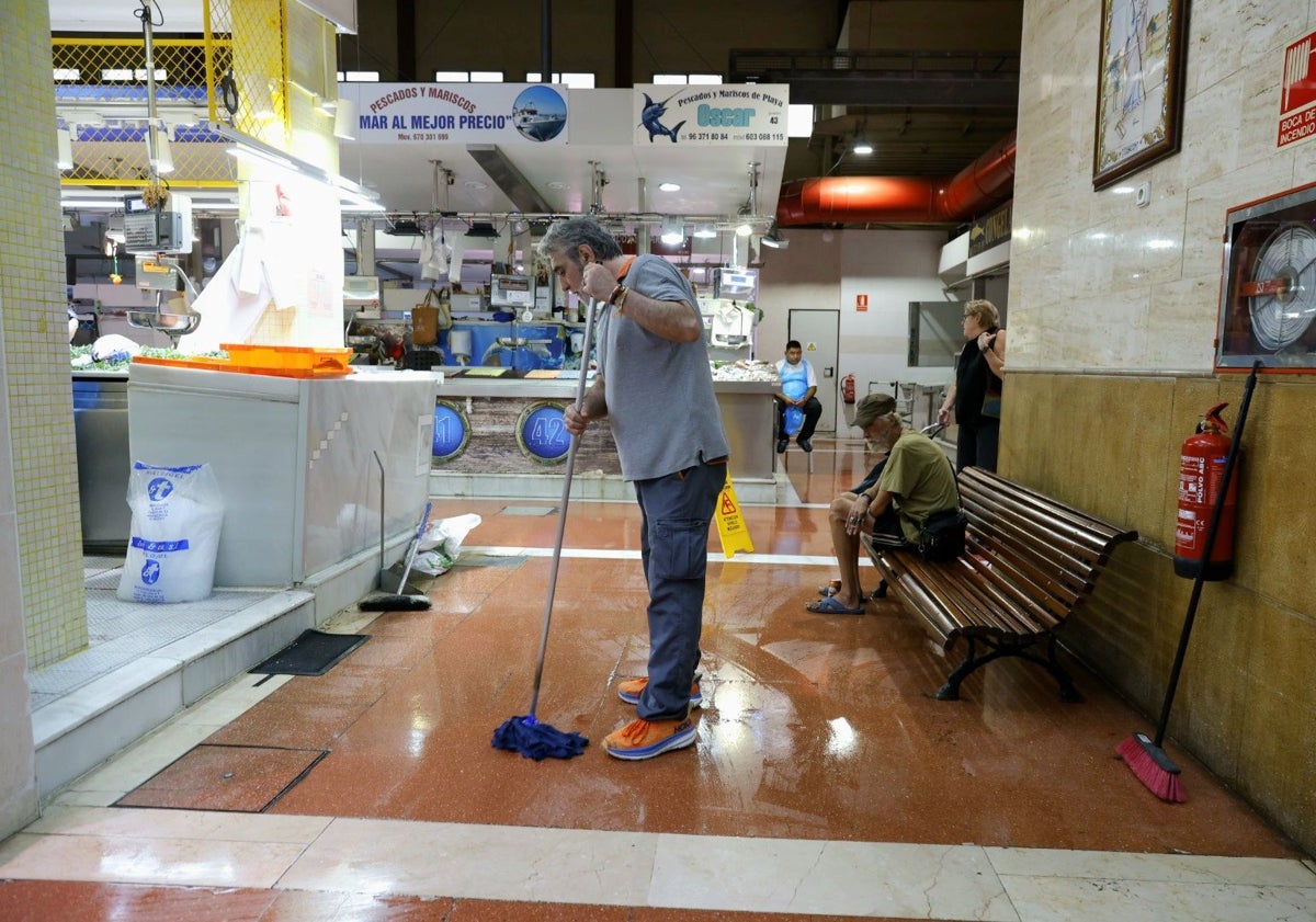 Imagen principal - Vendedores y operario municipal, retirando el agua en el mercado del Cabanyal.
