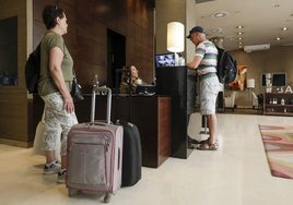 Dos turistas en la recepción de un hotel en Valencia.