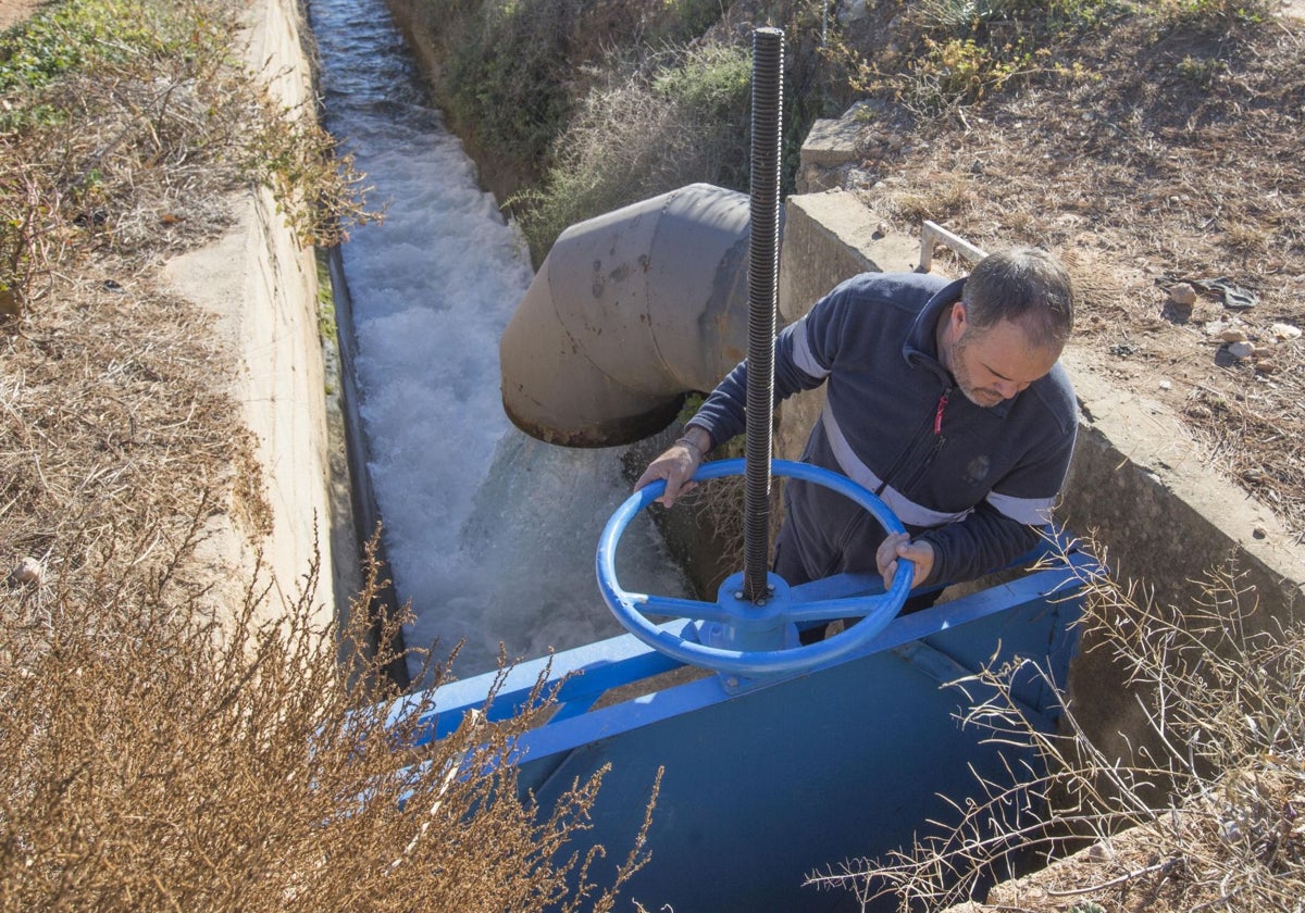 Un regante abre el paso de agua de una acequia.