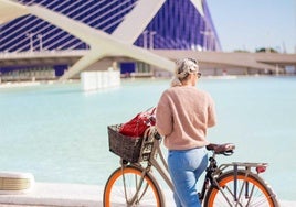 Una turista visita en bicicleta la Ciudad de las Artes y las Ciencias de Valencia.