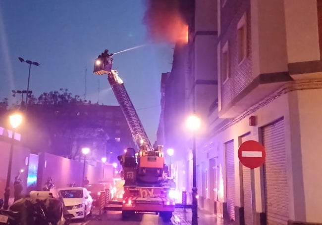 Un bombero ataca las llamas desde la escalera del camión en la calle Bello.