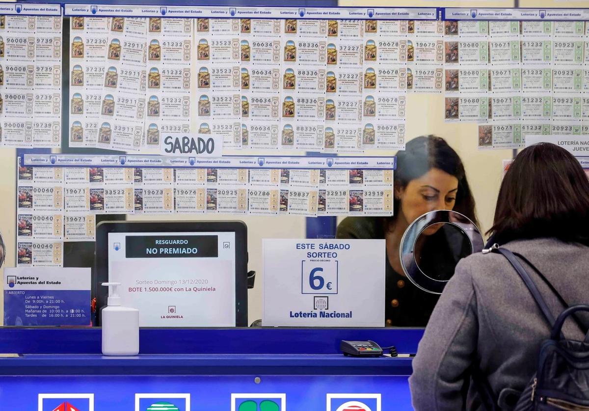 Una mujer compra un décimo en una administración de Lotería.