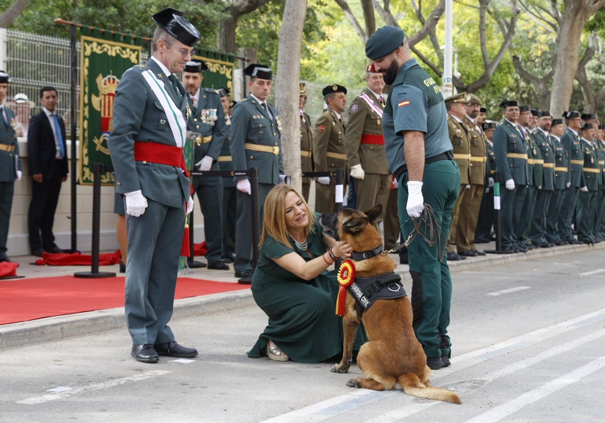 La delegada del Gobierno coloca la distinción al perro 'Beny'.