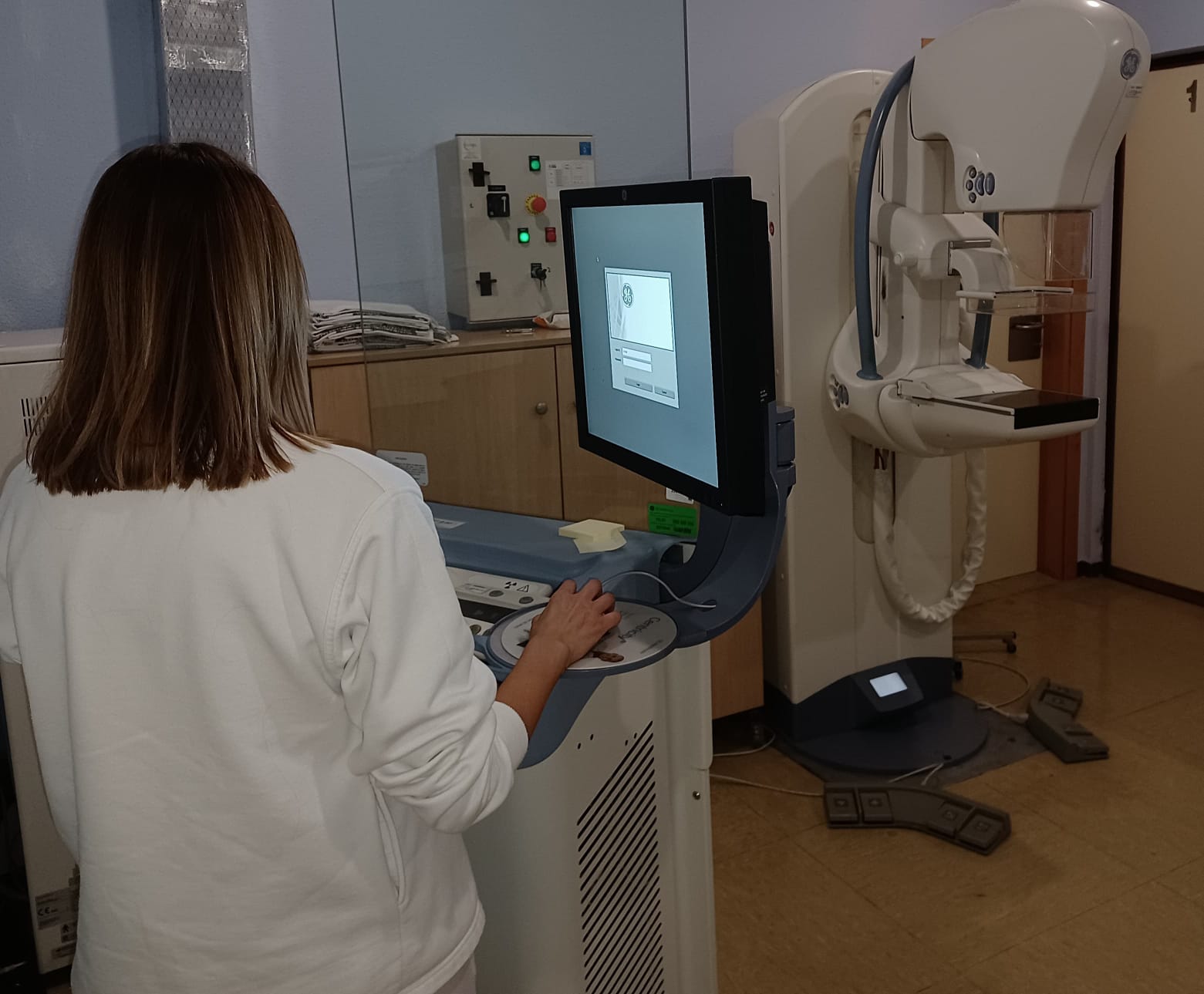 Sala de mamografía con una técnica manejando el mamógrafo.