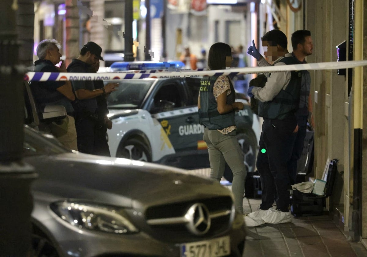 Guardias civiles y policías en la puerta del edificio donde tuvo lugar el crimen.