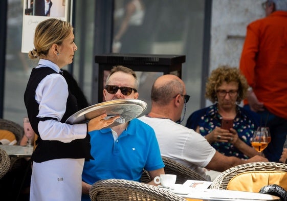 Una camarera atiende a un cliente en una terraza.