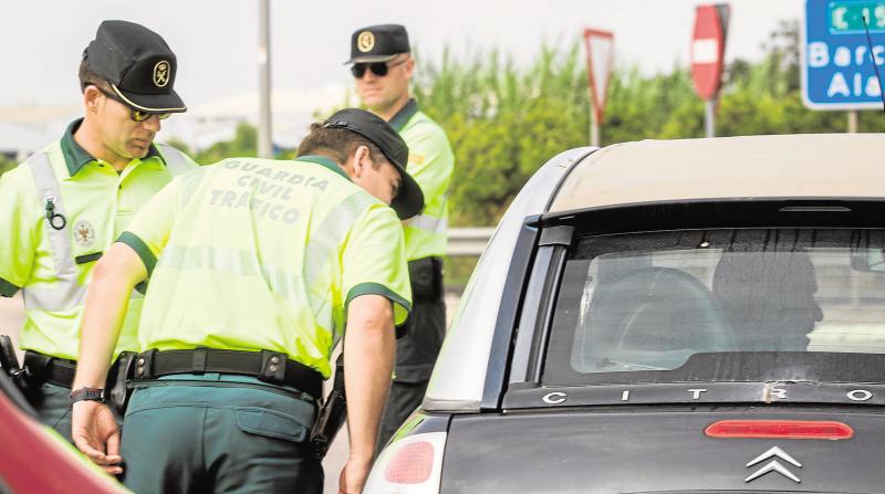 Un agente de la Guardia Civil de Tráfico inspecciona un vehículo.