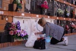 Una mujer limpiando un nicho en el cementerio.