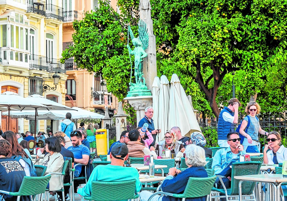 Personas sentads en una terraza de la plaza de la Virgen menos poblada de lo habitual.