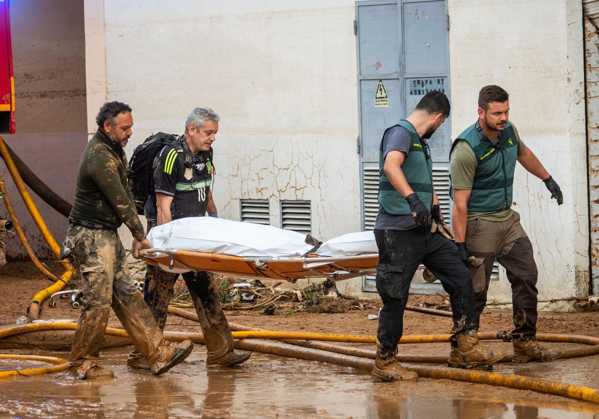 Equipos de rescate en Catarroja se llevan el cadáver de una víctima.