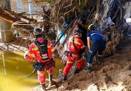 Miembros de los equipos de rescate buscan víctimas de la riada este sábado.