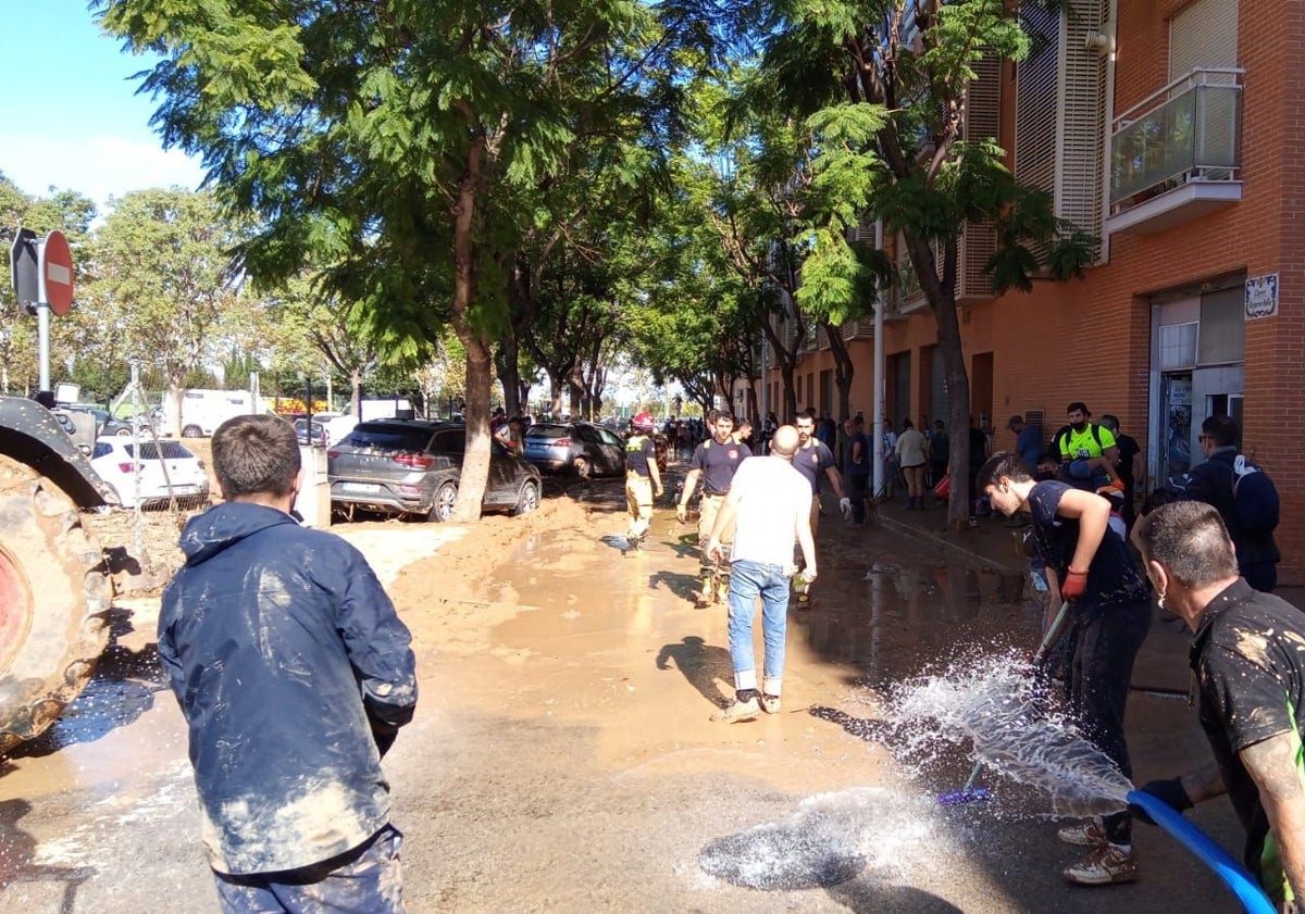 Imagen principal - Los vecinos, ayudados por bomberos voluntarios llegados de Alcorcón y policías también voluntarios, limpian las calles del barrio y sacan agua.