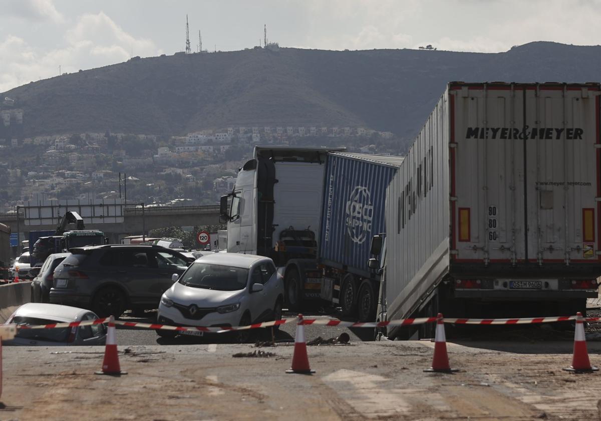 Socavón en el by-pass, donde quedaron atrapados varios vehículos tras la crecida del barranco. Al fondo, urbanización Calicanto de Torrent.