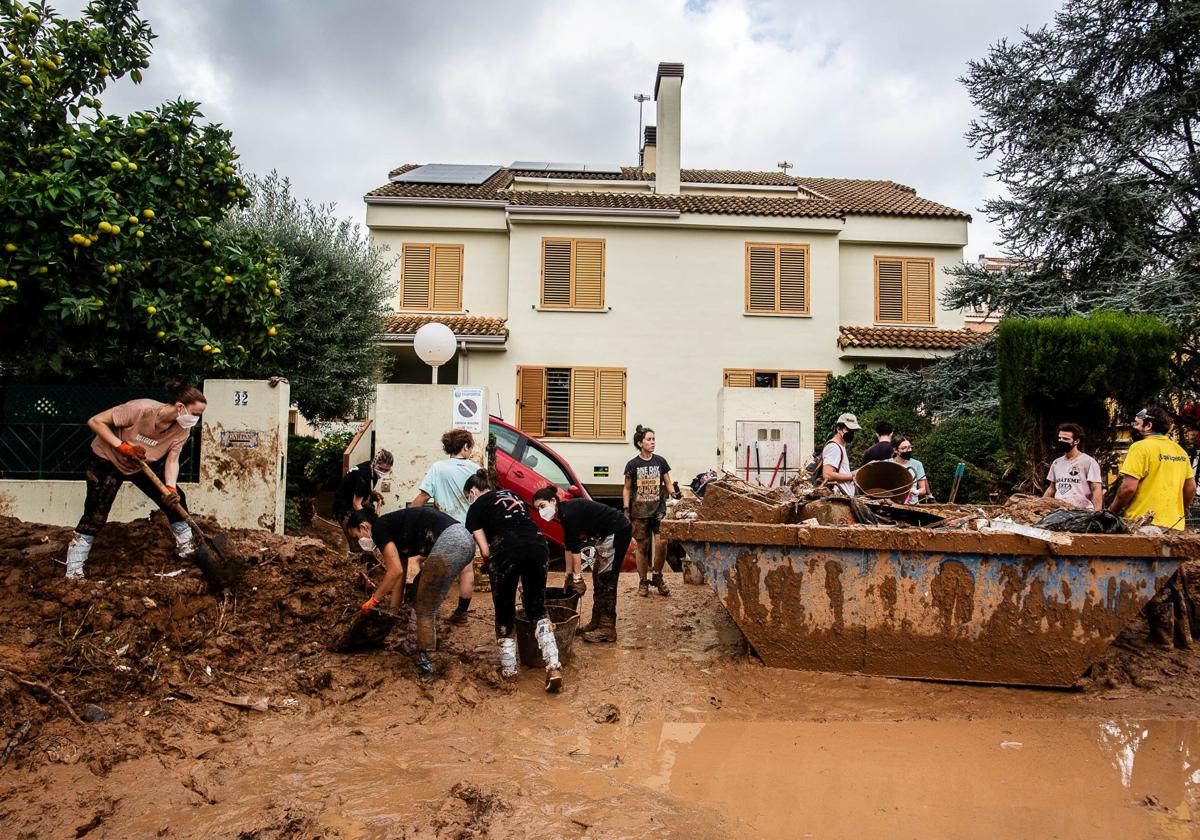 Un grupo de voluntarios limpia las inmediaciones de unas viviendas en Paiporta.