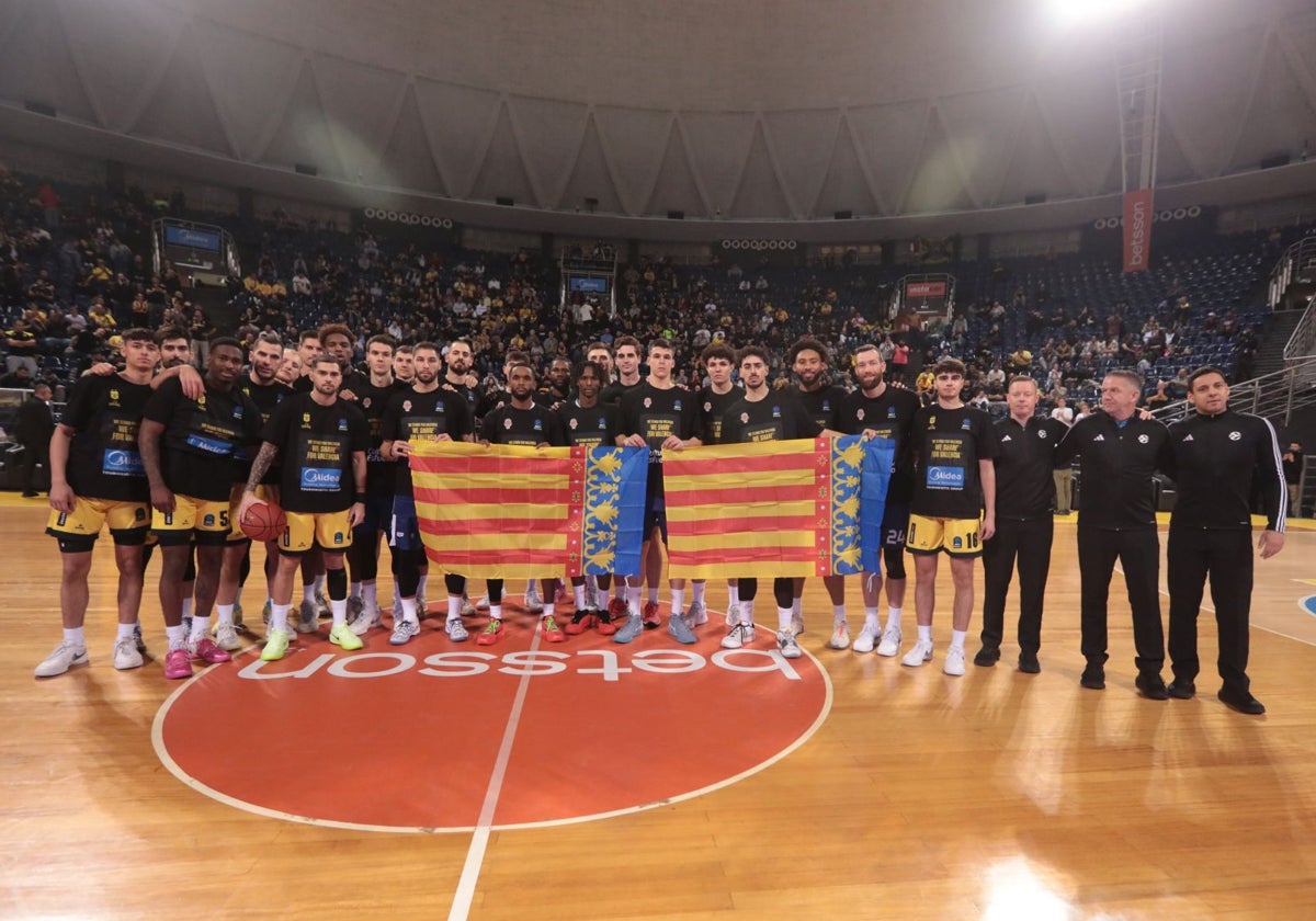 Los dos equipos, y los árbitros, posan con la Senyera antes del partido.